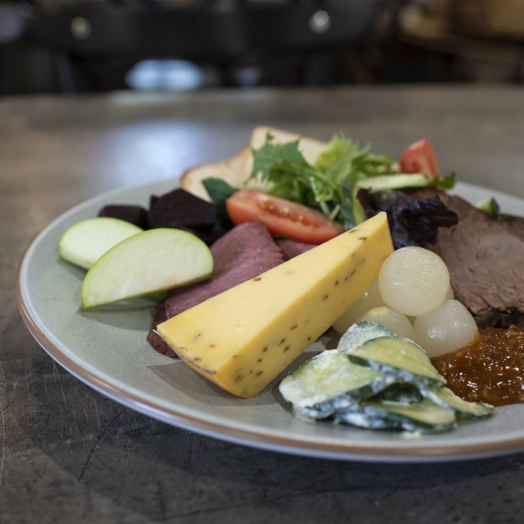 Plate with ploughman's lunch including meats, cheese and salad