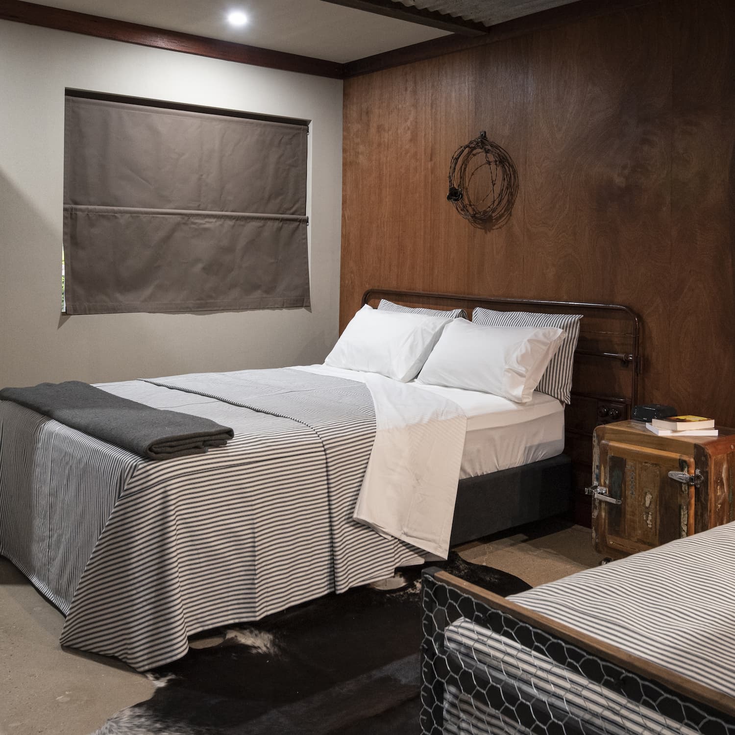 The Stables room interior with Queen bed, timber wall panelling and cow hide rug