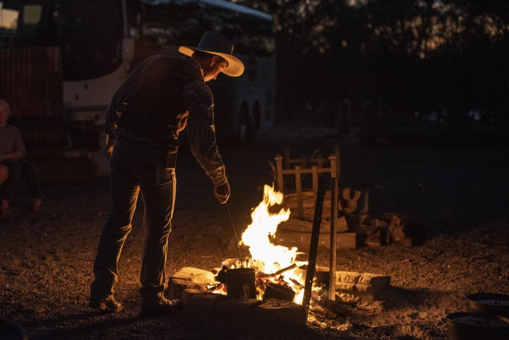 Man boiling a billy on an open campfire at night