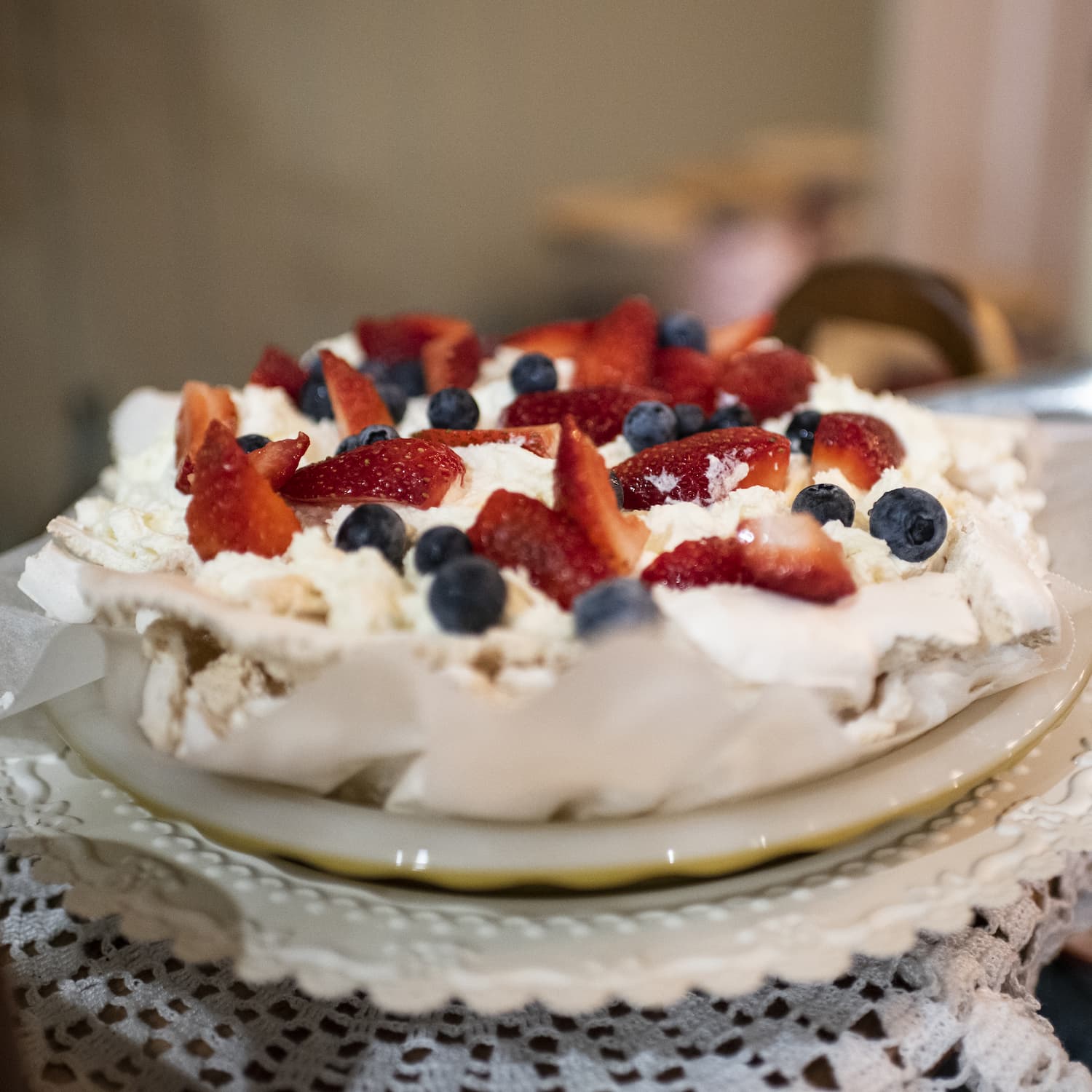Pavlova topped with cream, strawberries and blueberries
