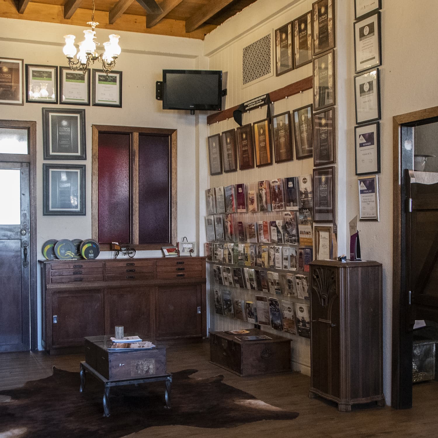 Internal of The parlour room at Outback Pioneers booking office. Walls showing tourism brochure racks