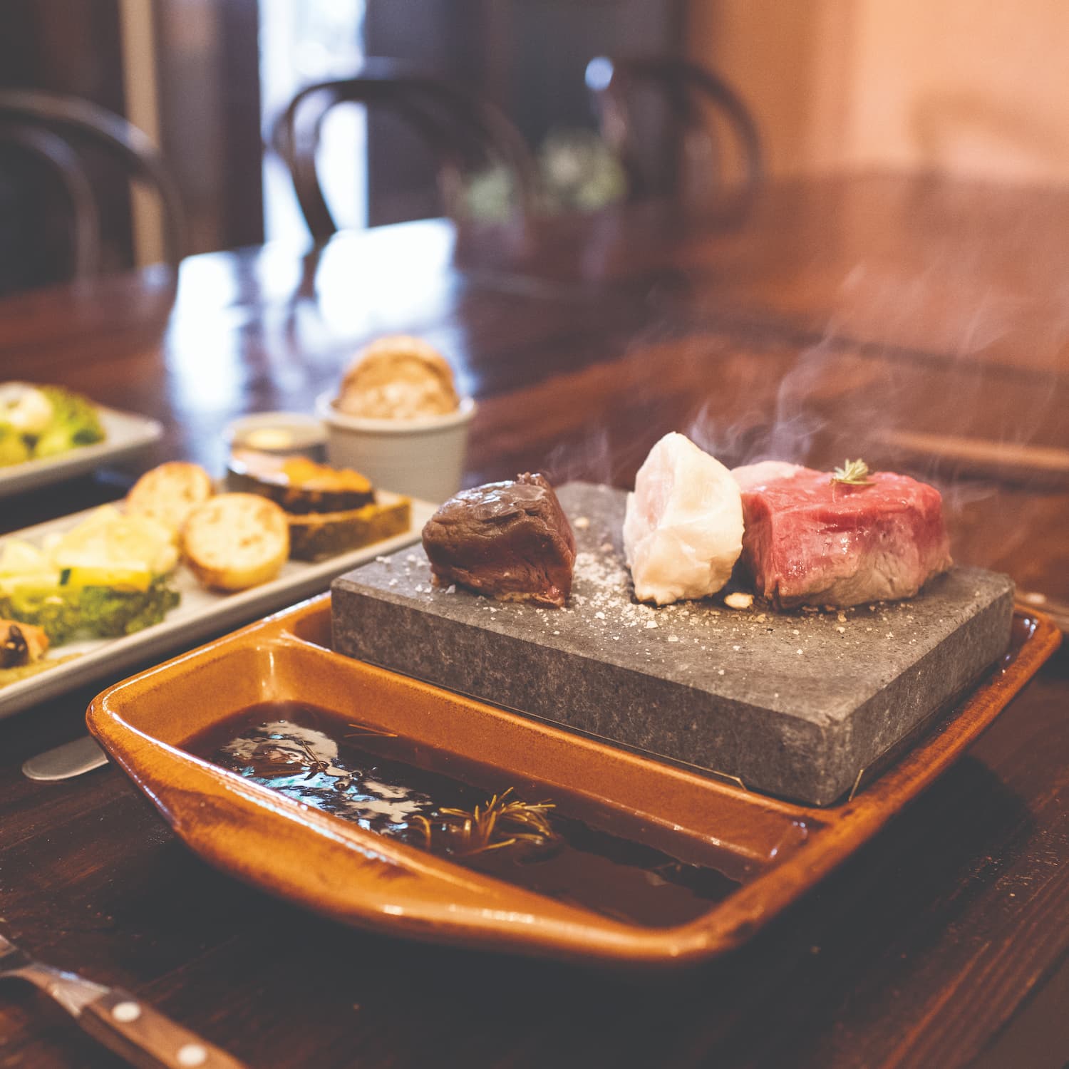 A piece of kangaroo meat, crocodile and steak cooking on a stonegrill