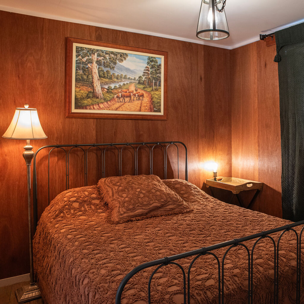 The Coach Inn queen bed with a lamp and a painting on the wall