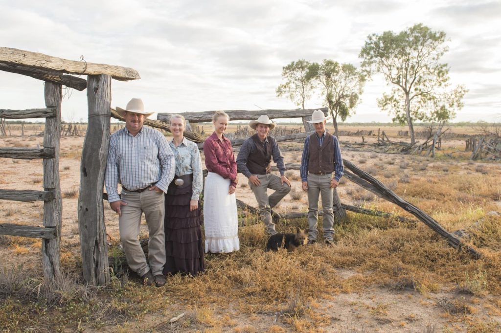 The Kinnon family leaning against timber railings, standing in outback paddock
