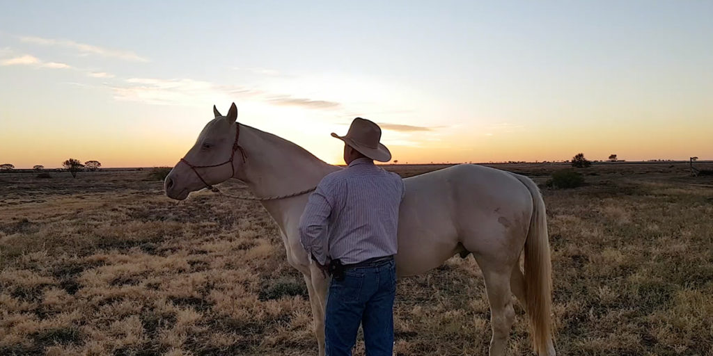 Richard Kinnon standing with his Cremello horse at dawn