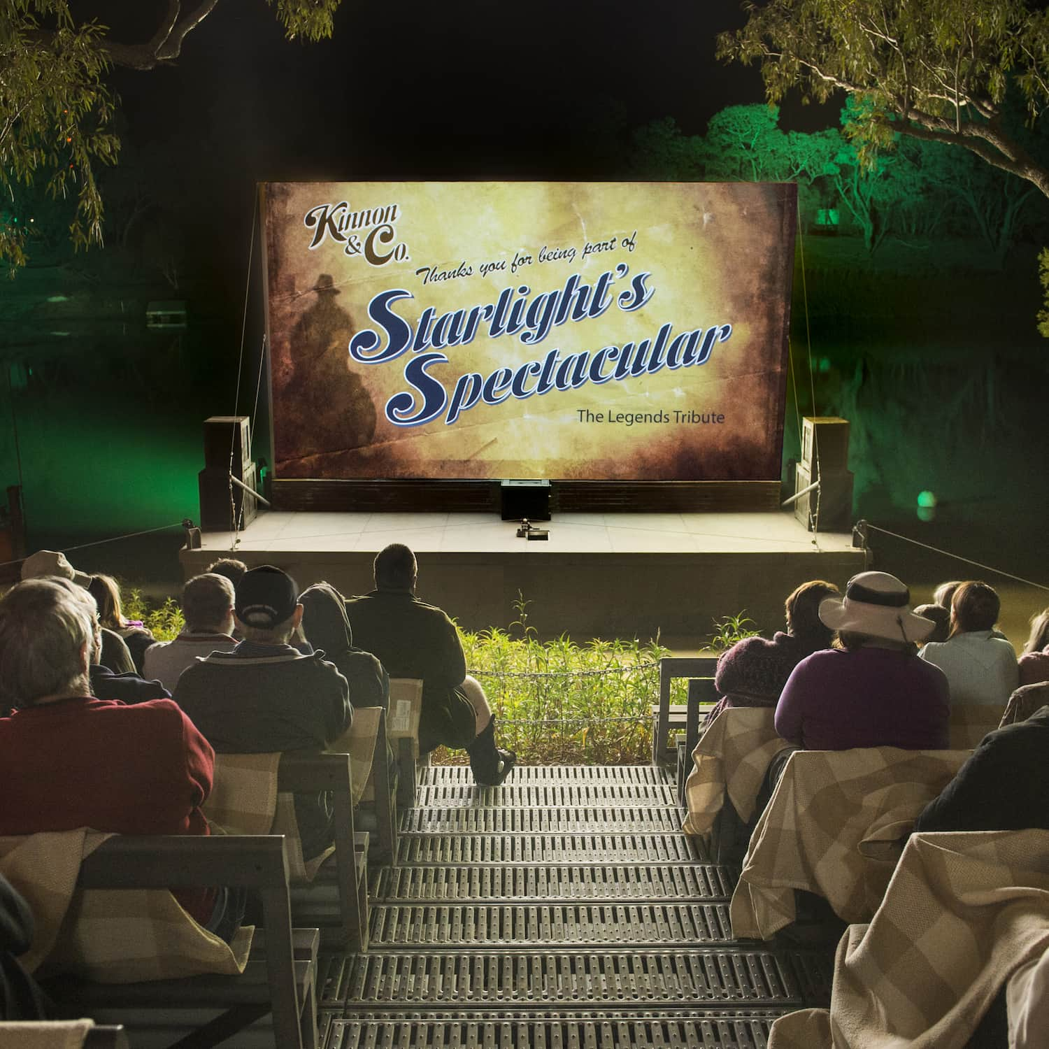 Illuminated river bank movie screen with guests watching at night