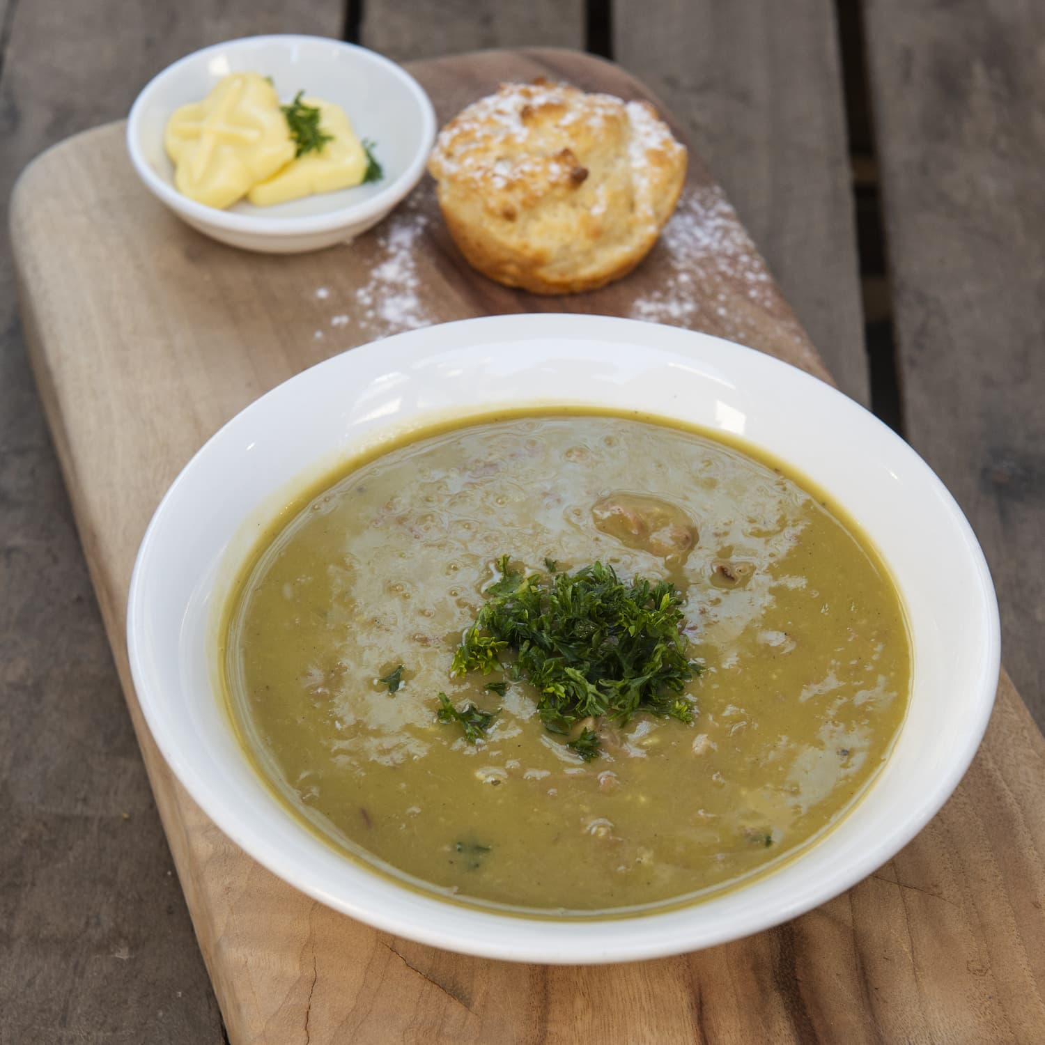 Bowl of pea and ham soup with damper and butter