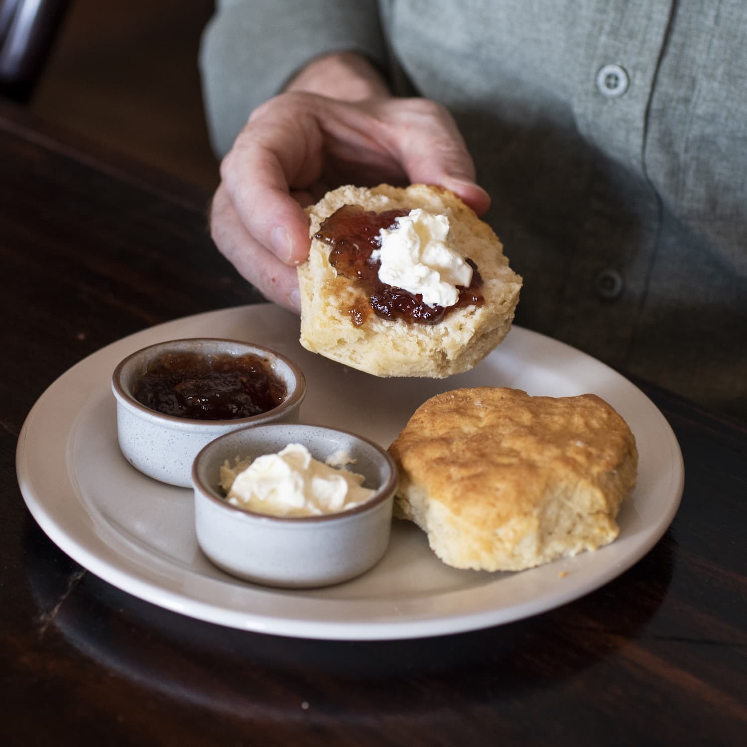 Man holding a scone with jam and cream