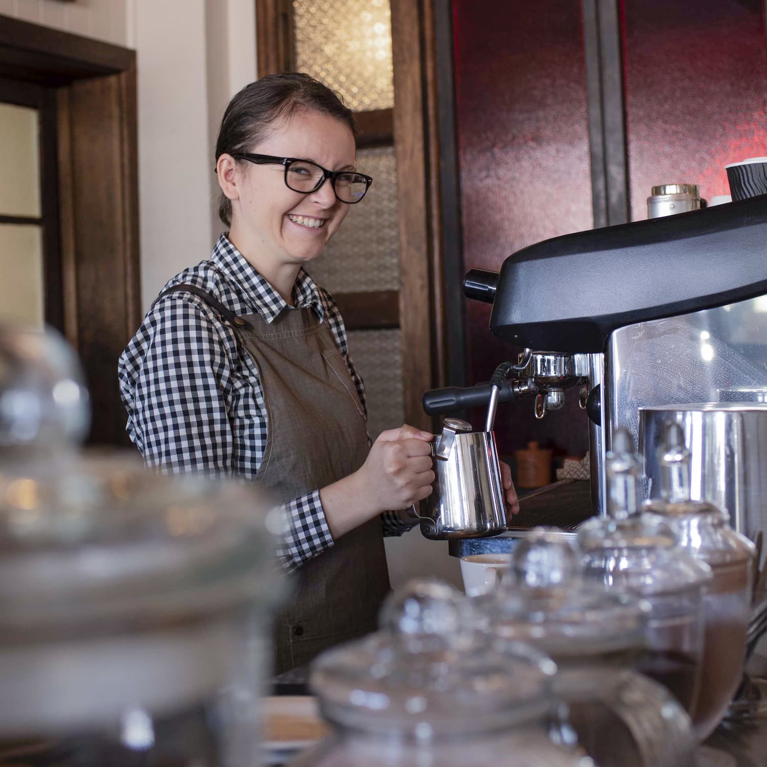 Young female barista smiling and making coffee