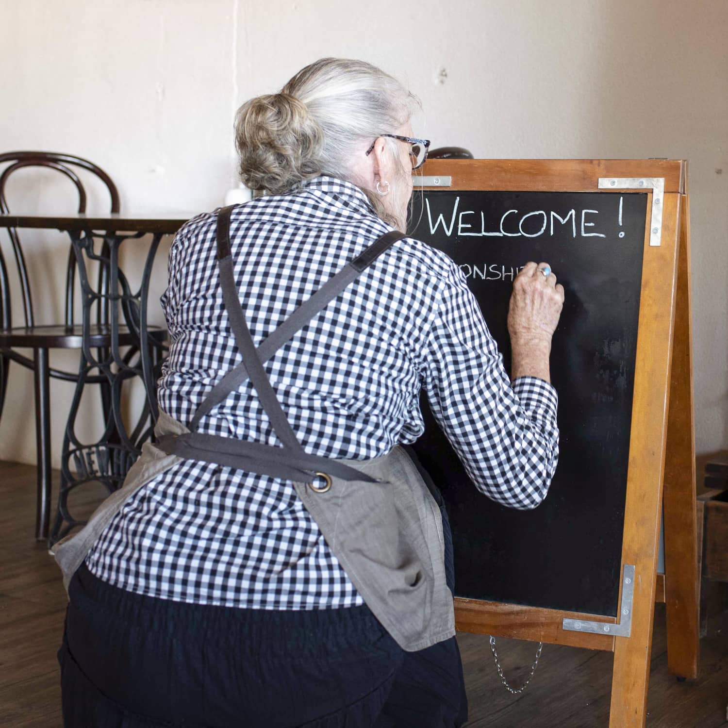Staff member writing 'Welcome' on an A-board