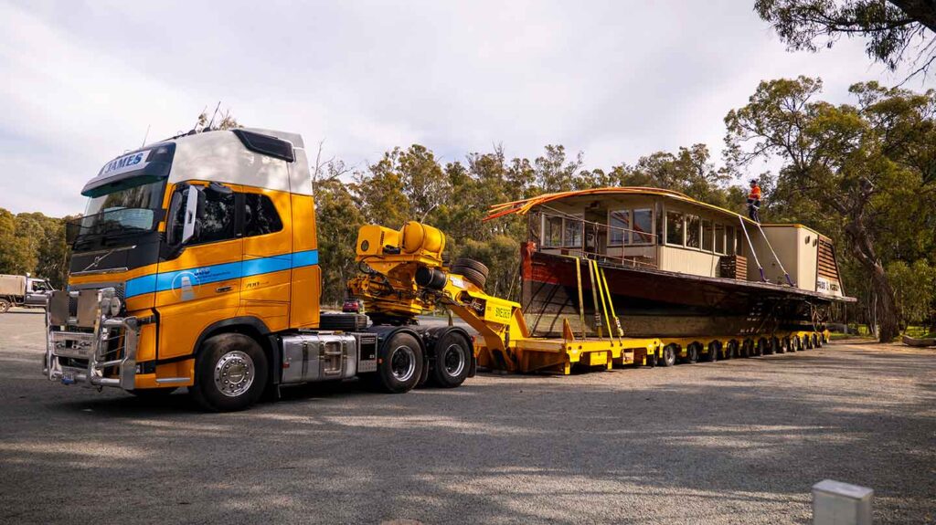 Low-loader truck with the Pride of the Murray paddlewheeler loaded on the back