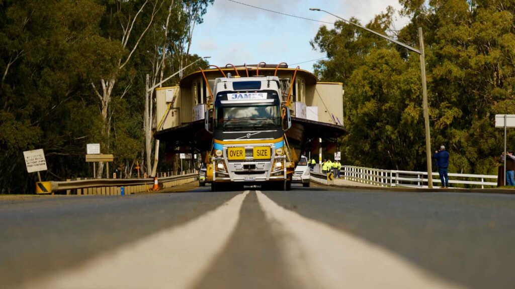 Low-loader truck travelling over bridge carrying 100-tonne paddlewheeler