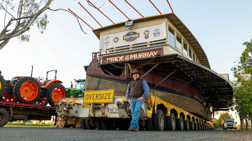 Pride of the Murray paddlewheeler on the back of a low-loader trailer. Richard Kinnon leaning next to the trailer.