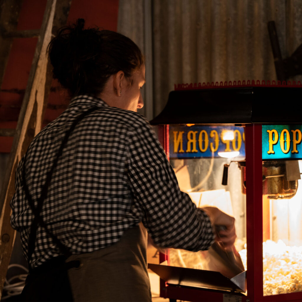 A woman serving popcorn from a popcorn machine
