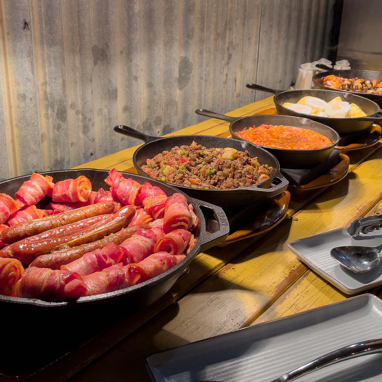 A row of pans containing breakfast foods under a heat lamp