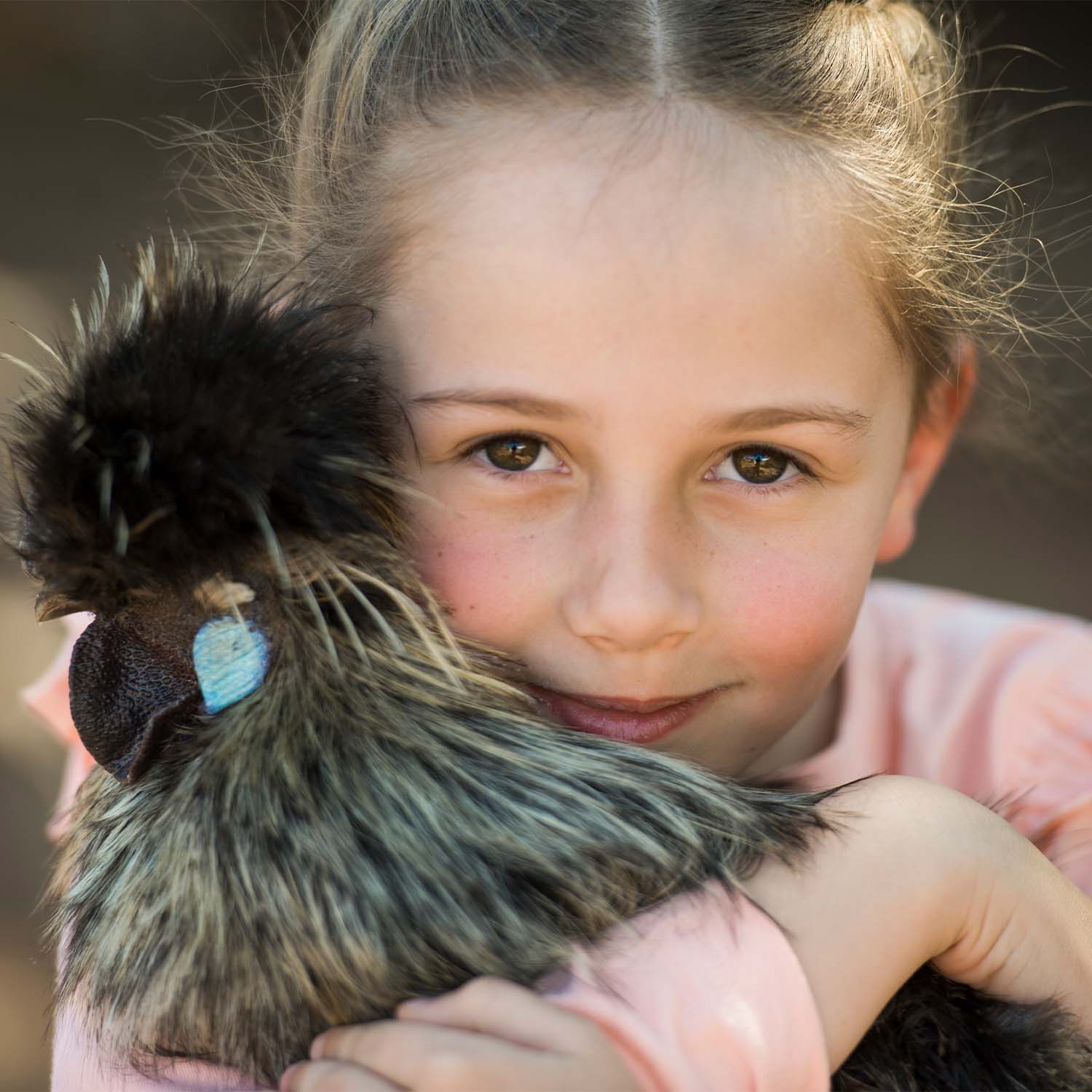 A young girl holding a chicken close to her