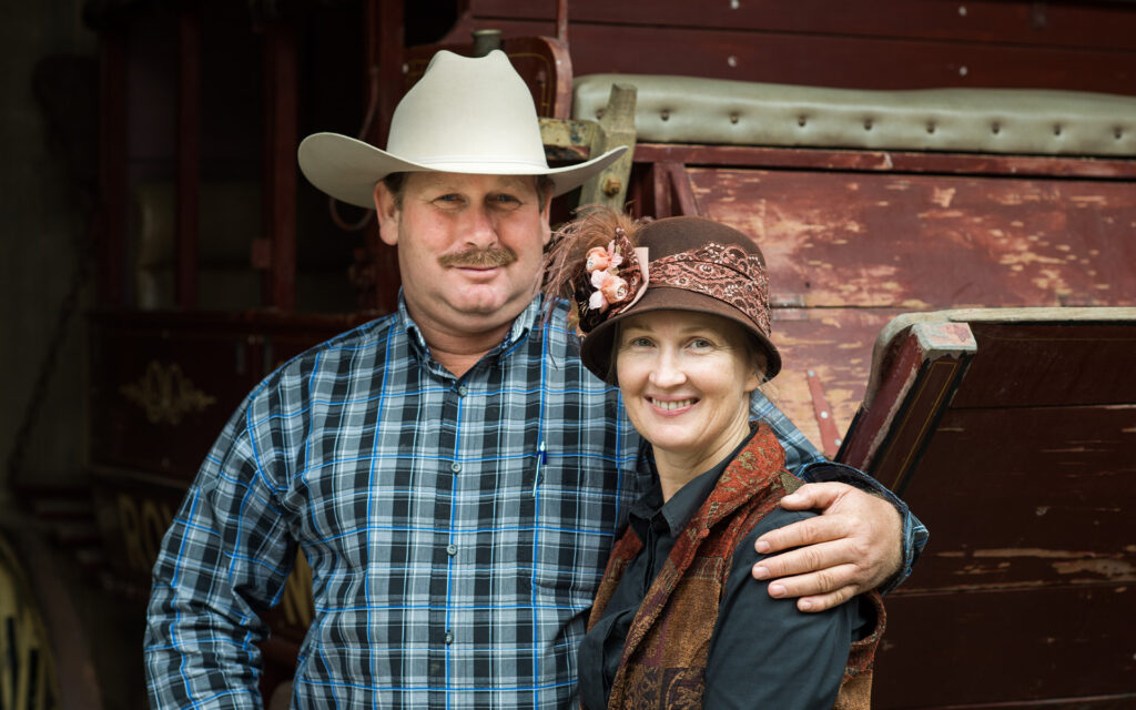 Outback Pioneers owners Marisse and Richard Kinnon standing in front of a Cobb & Co stagecoach